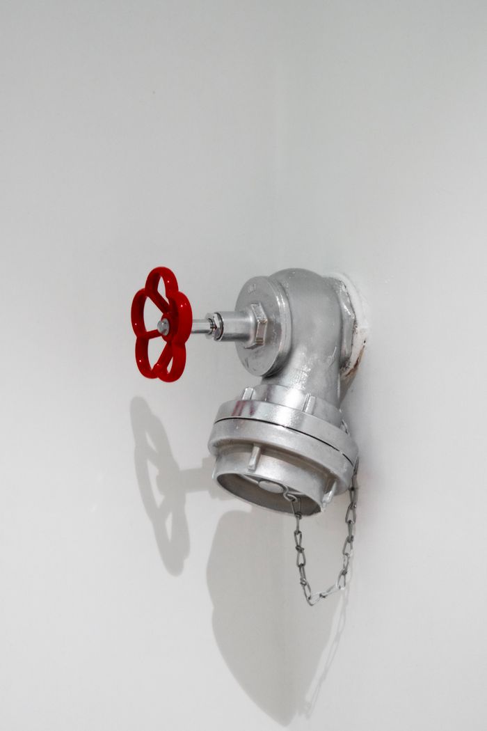 Services Detailed view of a silver plumbing installation with a red valve on a white wall in Eskişehir.